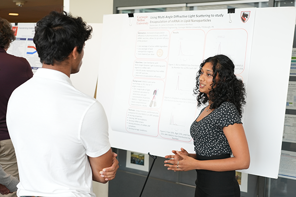 A student presents their research poster to another student