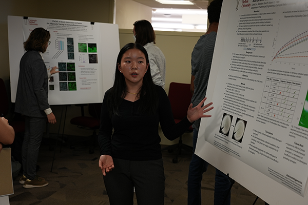 Student researchers present their posters in a conference room