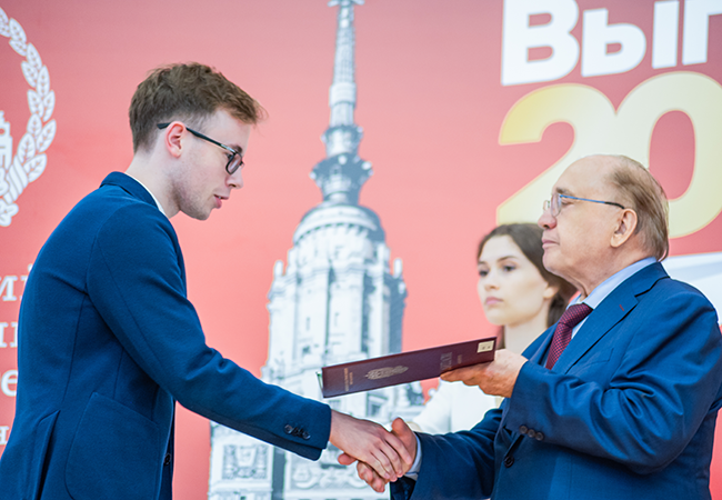 Daniil Boiko shakes hands with an older man who is passing him his diploma