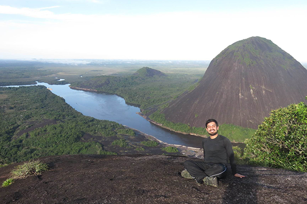 David Bernal Neira sits on a hilltop at Mavicure, with a river and hills in the background