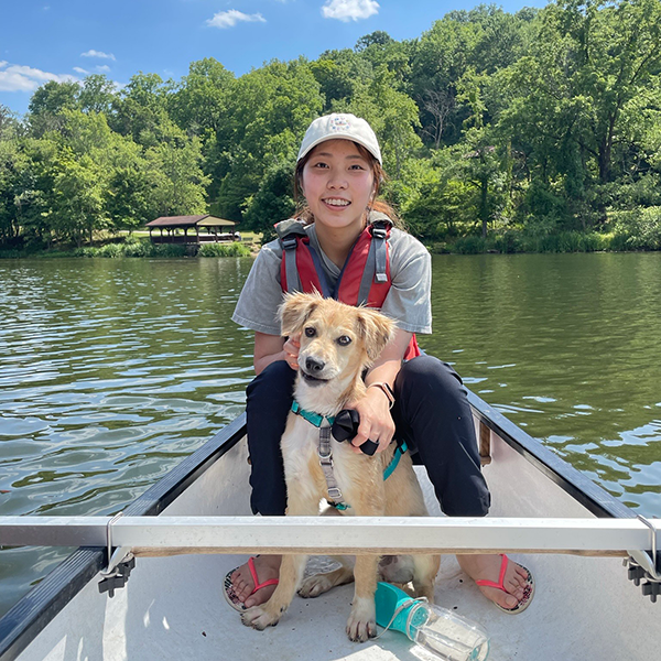 Lory Wang sitting in a canoe with a dog