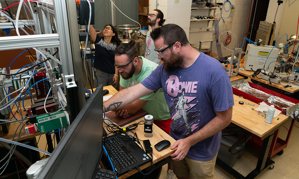 Four adults working with instruments and computers in a laboratory