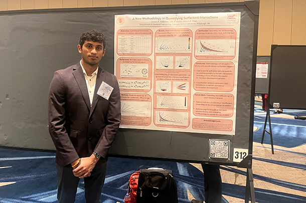 Chetan Chilkunda stands next to his research poster.
