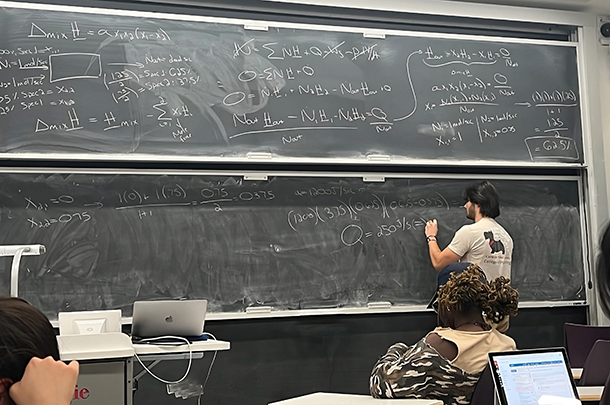 Aleksa Petric writing equations on a chalkboard in a classroom