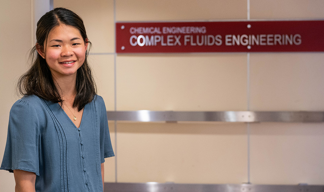 Irene Cui stands and smiles in front of a sign that reads Chemical Engineering Complex Fluids Engineering