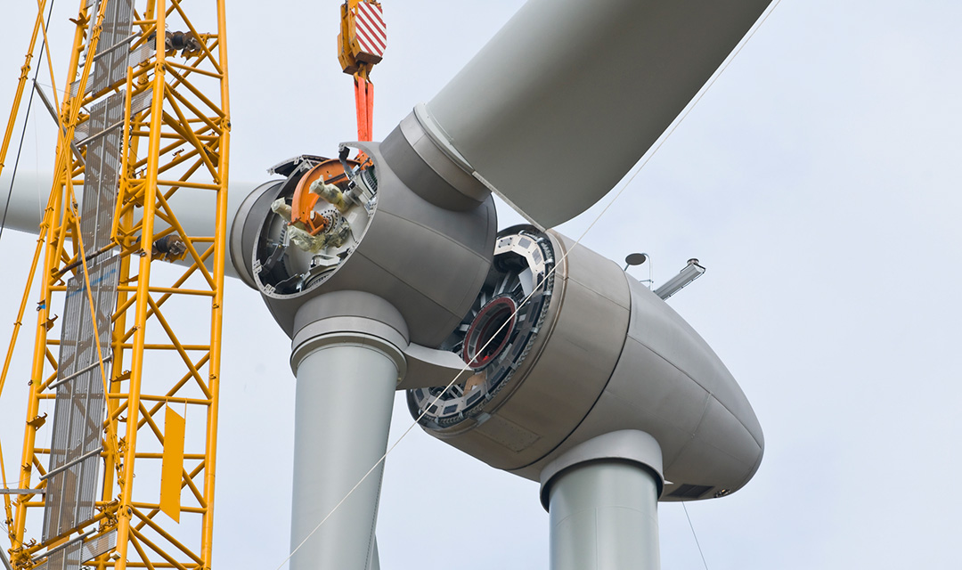 Partial view inside the nacelle and hub as rotor blades are installed on a wind turbine