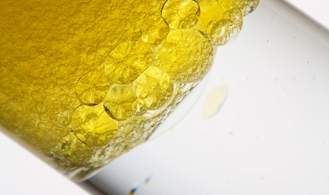 Close-up of a clear tube filled with a layer of bubbly yellow liquid and a layer of clear liquid.