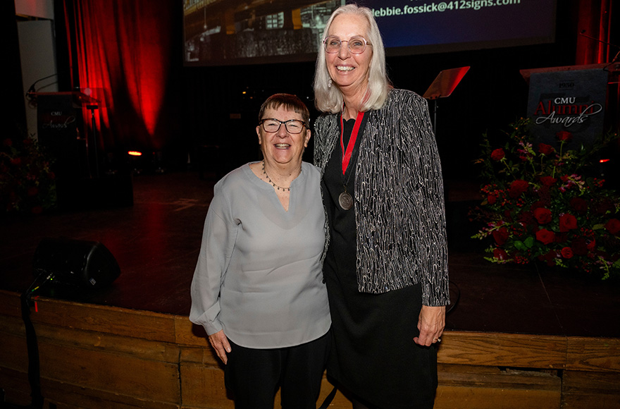 Two women stand together smiling.