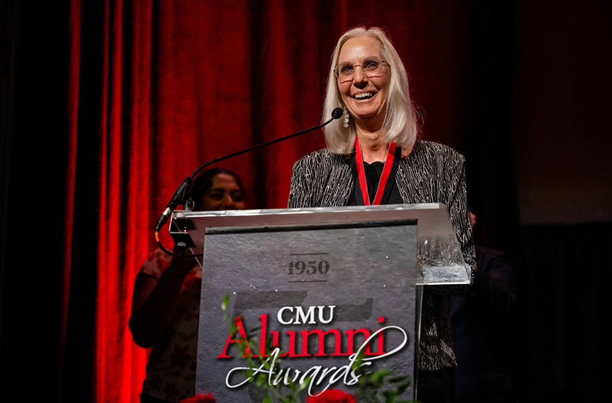 Joanna Livengood stands at a podium smiling.