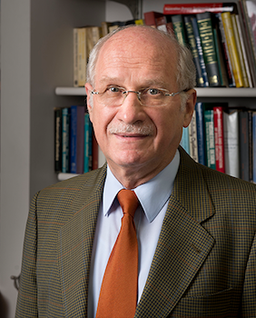 A man in a suit and tie standing in front of a bookcase