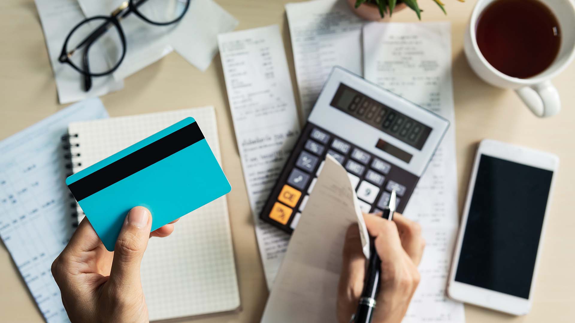 stock image of someone working on finances - calculator, phone, credit card, paper, pencil, etc. 